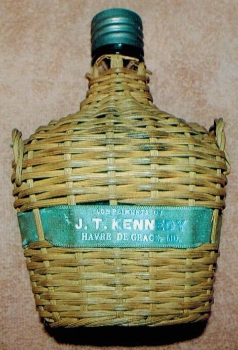 vintage bottle in a woven basket, J.T. Kennedy, Havre de Grace